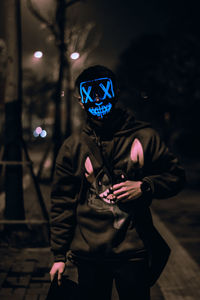 Portrait of the unknown man behind the neon mask at night. dark brown tone