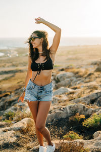 Woman wearing sunglasses while standing at beach during sunset