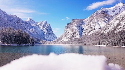 Scenic view of lake by snowcapped mountains against sky