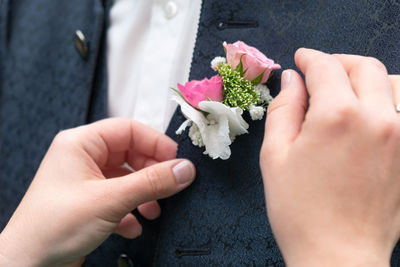 Cropped image of hand adjusting flower bouquet on suit