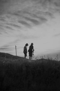 Rear view of men walking on land against sky