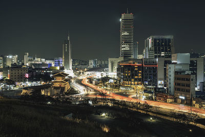 Illuminated buildings in city against sky at night