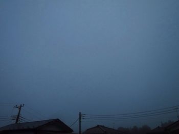 Low angle view of silhouette electricity pylon against clear sky