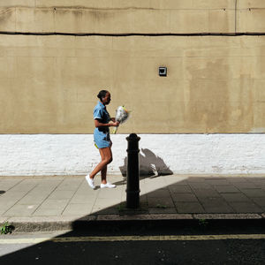 Full length side view of man walking on footpath