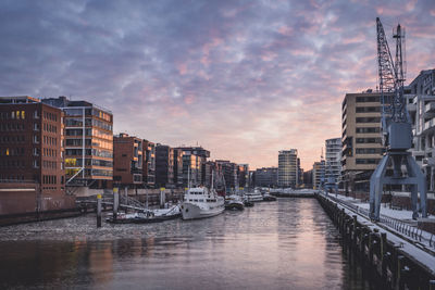 Canal amidst buildings against sky during sunset