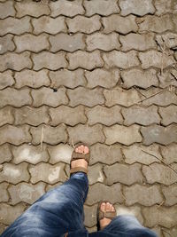 Low section of man walking on footpath during sunny day