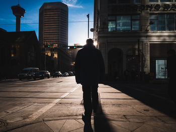 Rear view of silhouette man walking on street in city