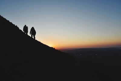 Silhouette people standing on mountain against sky during sunset