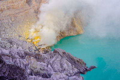 High angle view of smoke emitting from volcanic mountain