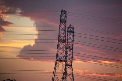 Low angle view of electricity pylon against cloudy sky