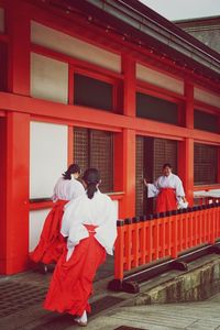 Rear view of friends standing against red wall