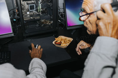 Elderly female and male friends playing computer game together at gaming lounge during weekend