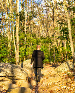 A young caucasian man wearing all black walking up a mountain path person