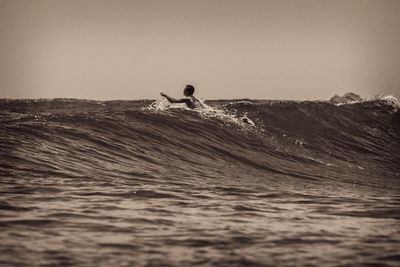 Man surfing in sea against clear sky