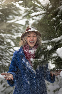 Portrait of smiling young woman standing against waterfall