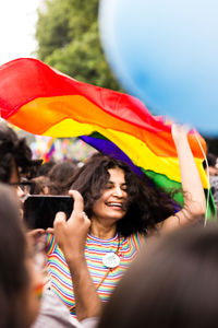 Woman holding multi colored umbrella while using smart phone