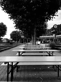 Empty benches in city against sky