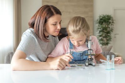 Mother helping daughter in science project at home