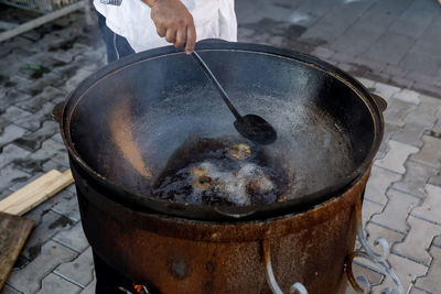 The adult chef prepares vegetables for pilaf in a cauldron in sunflower oil