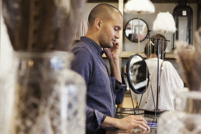 Side view of male owner talking on phone while standing at store