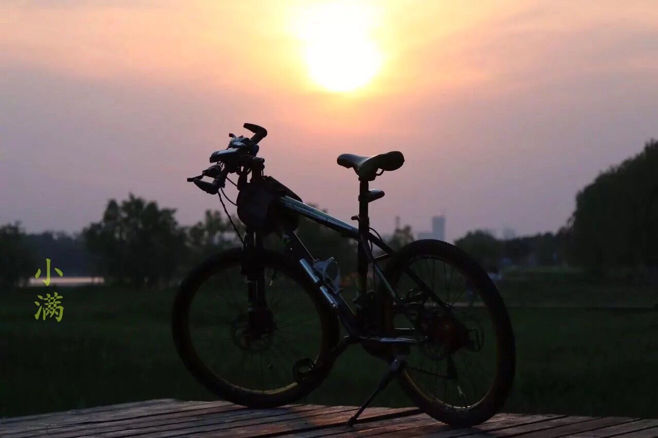 bicycle, transportation, mode of transport, land vehicle, sunset, stationary, parking, sky, parked, silhouette, tree, tranquility, landscape, orange color, no people, nature, field, cloud - sky, scenics, wheel