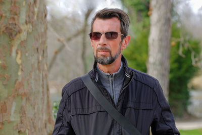 Portrait of man wearing sunglasses standing against trees