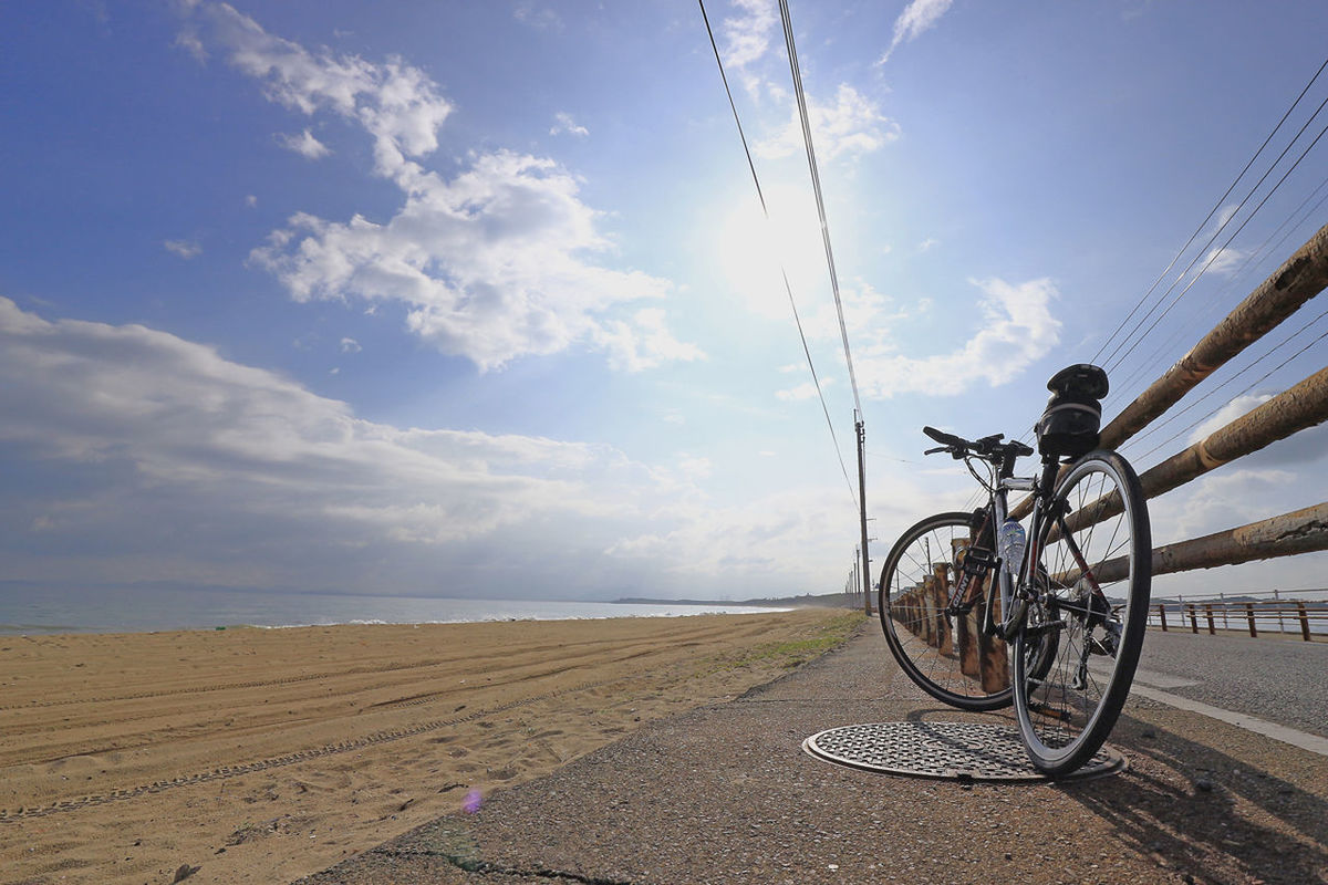 BICYCLE AT BEACH AGAINST SKY