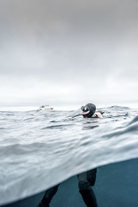 Man swimming in sea against sky