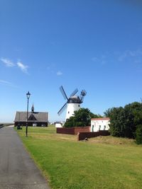 Traditional windmill on grassy field against clear blue sky