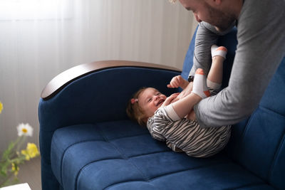 Caucasian man playing with cute baby and child, kid, toddler, having fun at home 