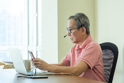 Man using mobile phone while sitting on table