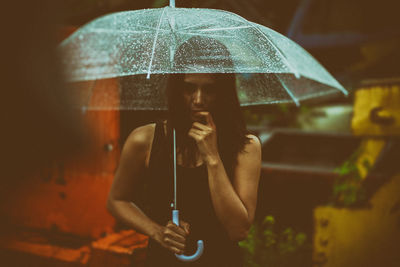 Midsection of woman holding umbrella during rainy season