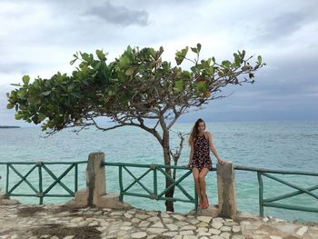 Woman standing by sea against sky