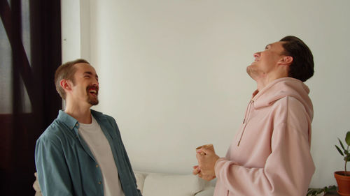 Smiling gay couple laughing at home