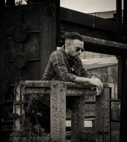 Man wearing sunglasses standing against abandoned building