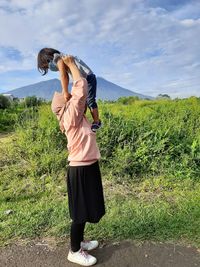 Side view of woman holding daughter mid air outdoors