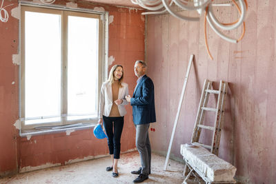 Male engineer and businesswoman working together while examining construction site