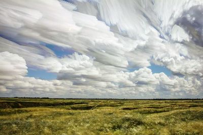 Scenic view of grassy field against cloudy sky