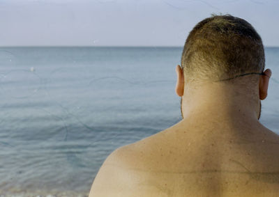 Rear view of shirtless woman in sea