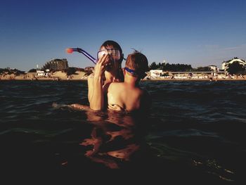 People at beach against clear sky