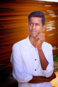 Portrait of young man standing against wall