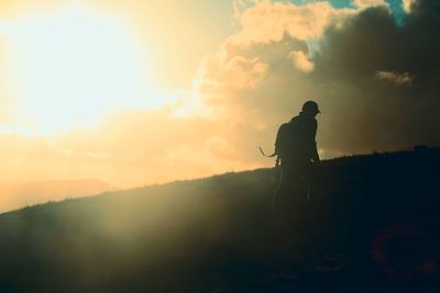 Silhouette of man on mountain against sunset sky