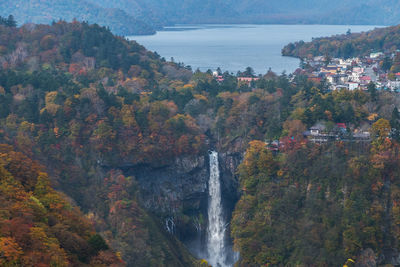 Scenic view of waterfall amidst tree and mountain by residential district