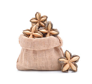 Close-up of star anise in sack against white background