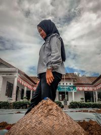 Man standing by building against sky in city