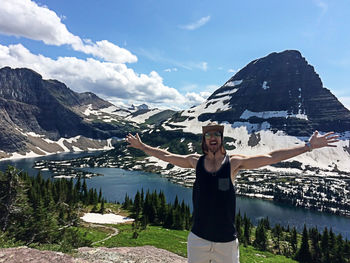 Excited man standing with arms outstretched against bearhat mountain at glacier national park