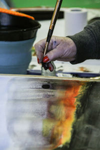 Cropped hand of woman painting on table