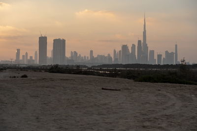 Modern buildings in city against sky during sunset