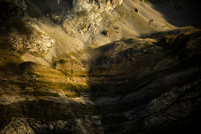 From above of solid uneven rocky mountain slope with sunlight and shadows for natural environment background and wallpaper