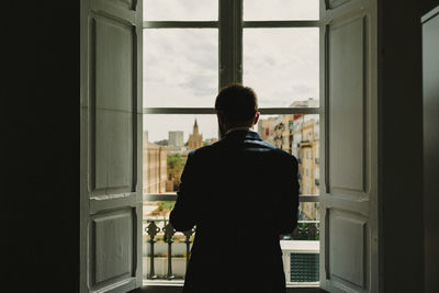 Rear view of man looking through window